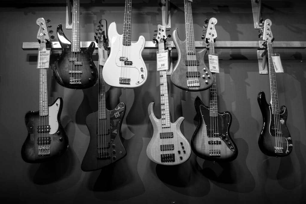 Black and white display of various electric bass guitars hanging on a rack. for parts of a bass guitar article